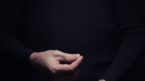 Male hand making money asking sign gesture rubbing fingers together on black background