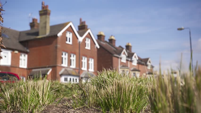 UK Suburban housing with grasses blowing in the wind in slow motion 