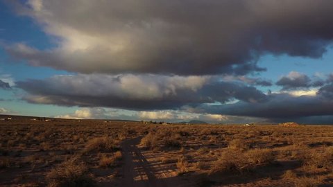 Low Aerial Drone Tracking Shot over golden hour Mojave Desert with storm clouds