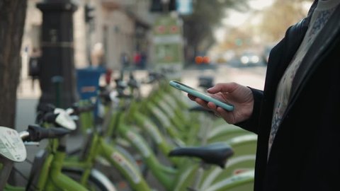 Female booking a public rental bicycle on mobile application