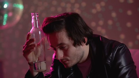 Man drinking vodka from bottle at party, suffering depression, alcohol addiction