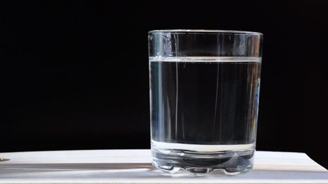 Effervescent tablet in a glas of water against a black background