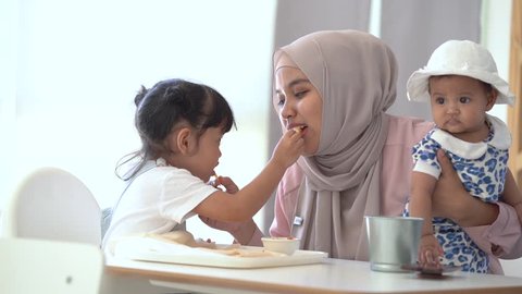 happy muslim family having a lunch together at home. single mom with two daughter concept.