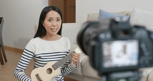 Woman teaching ukulele at home in front of camera