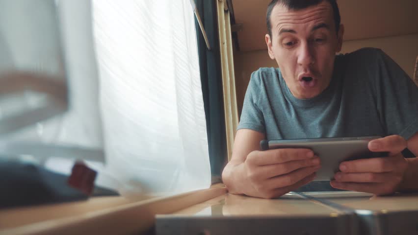 man playing an online game on a smartphone, strong emotions, anger man sitting in a train by the window. lifestyle slow motion video. train emotions joy surprise journey concept - Powered by Shutterstock - Get 15% off with code: PIKWIZARD15