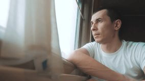 man rides train railway looks out the window. lifestyle traveler concept train railroad journey travel. slow motion video. beautiful from window of a moving train railway trip Russia winter