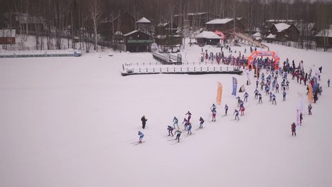 Pavlovka. Bashkortostan / Russia - February 19 2019: Start many peaple on massive ski marathon long distance at winter cloudy day - Aerial drone view