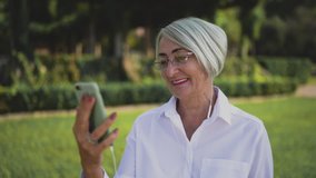 Happy attractive senior woman uses smartphone having a video chat