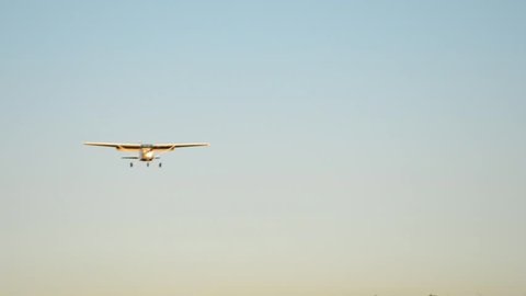 Small airplane approaching with blue sky and landing at the airport with sunset.