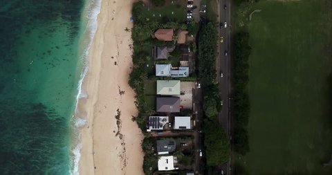 Aerial View: Section of Coastline with Clear Ocean, Beach, Buildings, & Road in Oahu, Hawaii