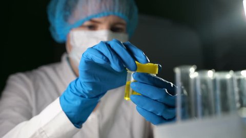 A demonstration video of a medical laboratory scientist dropping a sample of urine into a cup.