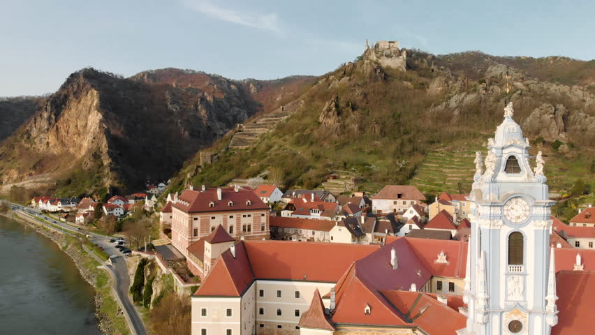 Aerial panoramic footage of the historical town of Dürnstein with famous Danube river in idyllic Wachau Valley in scenic golden evening light at sunset, Lower Austria region, Austria, central Europe