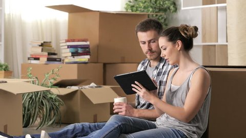 Happy couple moving home using a tablet to plan reforms sitting on the floor