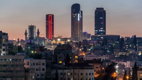 AMMAN, JORDAN - CIRCA 2019: Amman city skyline with Abdali district skyscrapers in the background. Day to night time lapse video. Illumination switch on.