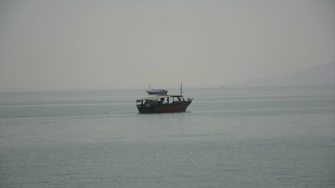 Two old fashioned boats sailing past each other on the Sea of Galilee in Israel. Reproductions of 2000 year old fishing boats.