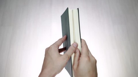 Two hands opening a book with blank pages. Two hands opening a blank book. Blank template for rotoscoping words inside an open book. Holding a book with two hands, it is opened and then closed.