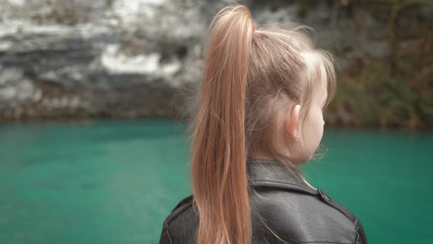 Child girl looking at beautiful lake. Spring family vacation. Little girl on scenic hike trail. Outdoor fun, lifestyle.