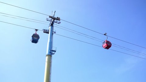 Two Aerial Tramway or Gondola Passing Each Other With Blue Sky in Background. Two Track Red and Blue Sky Tram or Cable Car Pass Through Each Other