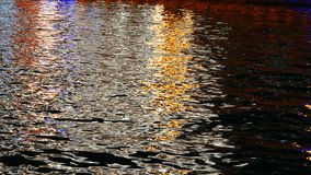 Colored glare on the water. Colored glare on the water in the light of the night illumination of the city. Abstract video.