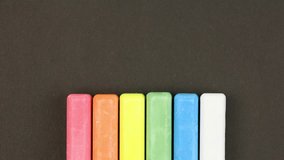 six colored children crayons on black background lined in a row, crayons come out  randomly, closeup, loop video, stopmotion animation, kindergarten education concept