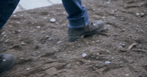 Slow motion close up of man's feet in boots walking on sand on construction site 4k