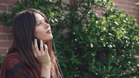 Beautiful young Woman talking to the phone,outdoors, brick wall background, Slow motion clip with gimbal
