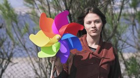 Beautiful young Woman Holding a Colorful Windmill outdoors in the Park, Slow motion clip