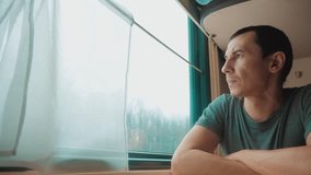 man travel rides train railway looks out the window. traveler concept train railroad journey travel. slow motion video. lifestyle beautiful from window of a moving train railway trip Russia winter