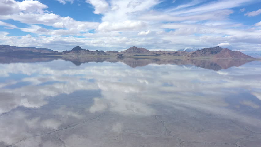 Aerial view flying low over water covering the Bonneville Salt Flats as the sky reflects in the water in Utah.