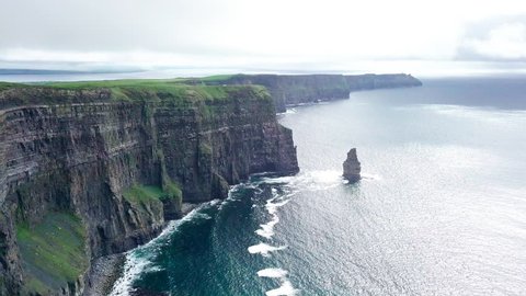 Aerial drone footage in 4k of the Cliffs of Moher in Ireland. Follows the walkway and hikers on the cliff's edge, approaching O'Brien's tower with the Branaunmore sea stack visible