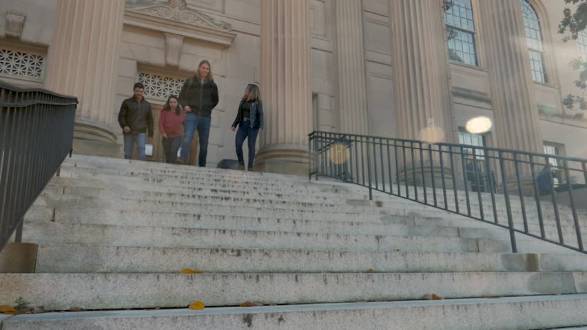 Two young men and two young women walking down library stairs in slow motion