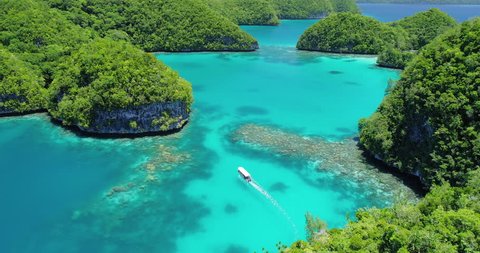 Aerial shot of boat travelling through tropical lagoon and islands in Palau