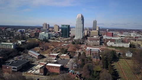 Aerial flying toward Winston Salem North Carolina with the city looming in the distance.