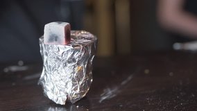 Close-up video as man is making a hookah. He is warming a coals and making a hookah bowl which is wrapped in a foil.