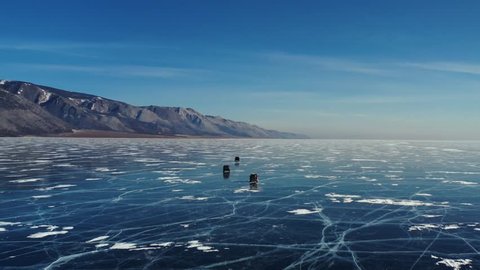 Aerial Perspective View of Cars Driving on Beautiful Deep Blue Ice Textured Frozen Baikal Lake Surface from above Captured with a Drone at Sunny Winter Day in Russia