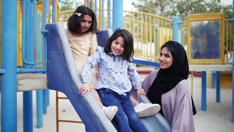 Mom and daughters spending time torgether at the park, playing at the playground and reading stories, Family moments in dubai