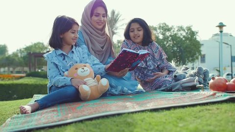 Mom and daughters spending time torgether at the park, playing at the playground and reading stories, Family moments in dubai