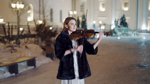 Playing violin instrument in the winter time. Passionate girl, portrait. Creating music