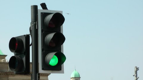 UK road crossing traffic lights from red, amber, green. filmed In busy city street. Medium shot.