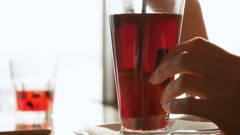 close-up. a glass of mulled wine. female hands mix drink a straw