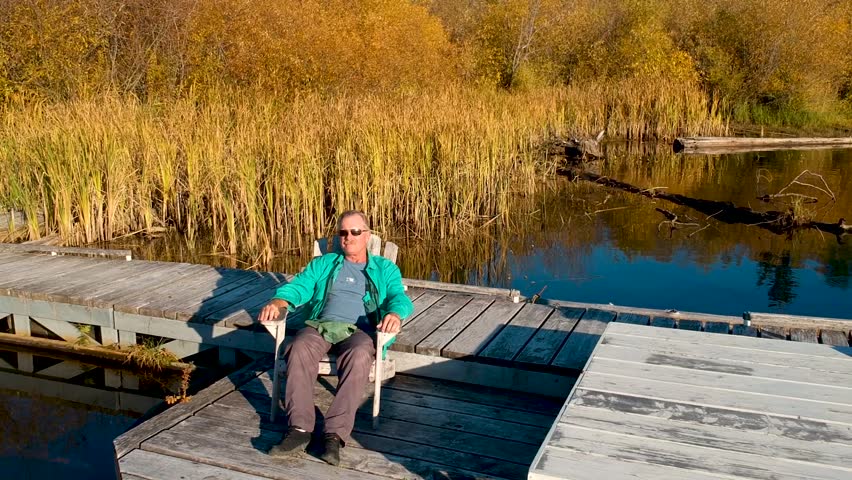 Man sitting on dock at sunset