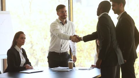 Company representative handshake diverse partners introducing coming at group meeting, caucasian businessman shake hands welcome african negotiator get acquainted express respect start negotiation