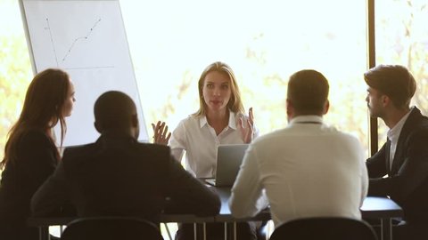 Female business coach mentor teacher talking at diverse staff group office meeting sit at table, executive manager boss leader training employees interns consulting clients at team corporate workshop
