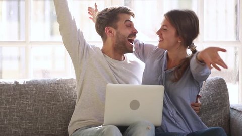 Excited happy young family couple looking at laptop computer feel winners surprised by lottery betting winning bid, celebrate good internet news embracing overjoyed by victory achievement online