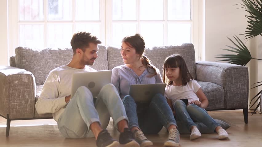 Happy modern family sit on floor in living room talking using devices, parents mom dad and child daughter having fun with laptops and phone at home, people and gadgets, technology addiction concept Royalty-Free Stock Footage #1028009612