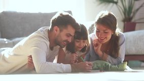 Happy family young parents drawing coloring picture with pencils helping cute child daughter enjoying talk play laying on warm floor at home, mom dad and kid girl having fun in living room on leisure - Powered by Shutterstock - Get 15% off with code: PIKWIZARD15