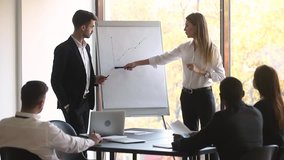 Two professional business coaches company leaders teachers give flip chart presentation explain graph consult clients training workers group at conference meeting office team workshop in boardroom - Powered by Shutterstock - Get 15% off with code: PIKWIZARD15