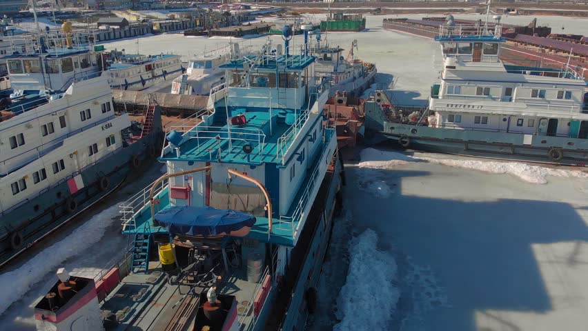 winter standing of logistic ships, cargo ships with a crane, boats, cargo barges, aerial filming from a copter on a sunny day