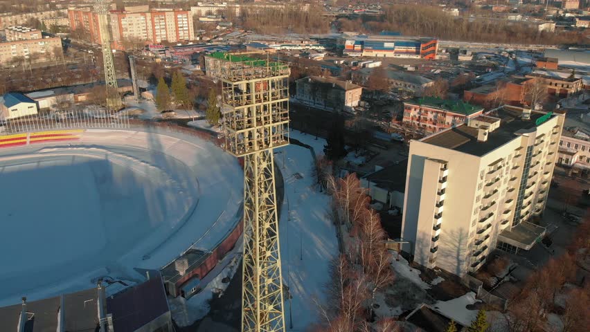 open stadium in the winter, a tower with spotlights, aerial shooting from the copter