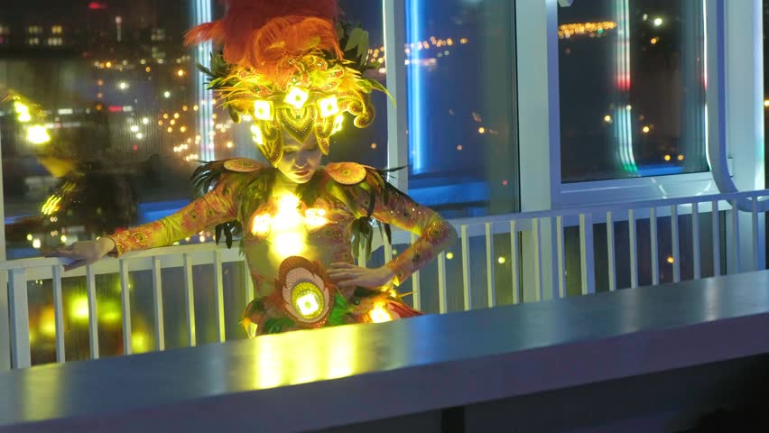  woman in a glowing costume is preparing for a performance, club or carnival dances